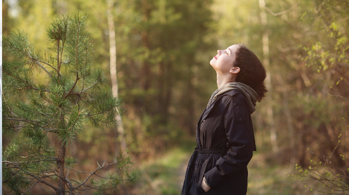 kobieta patrzy w niebo w lesie